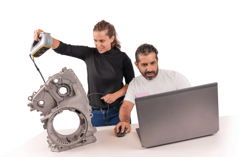 Engenheira utilizando scanner 3D portátil para digitalizar peça mecânica enquanto colega analisa os dados no computador.